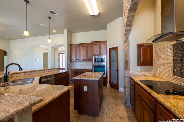 kitchen featuring appliances with stainless steel finishes, sink, light stone countertops, a center island, and exhaust hood