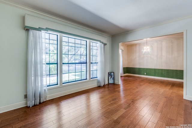 unfurnished room featuring ornamental molding, an inviting chandelier, and hardwood / wood-style floors