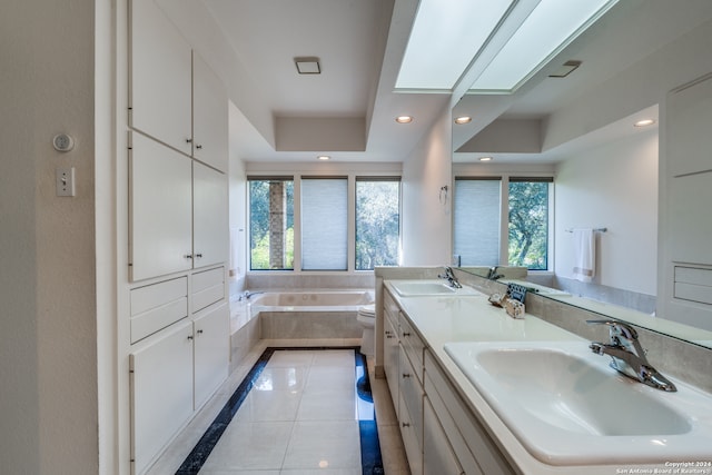 bathroom with a wealth of natural light, vanity, tiled tub, and toilet