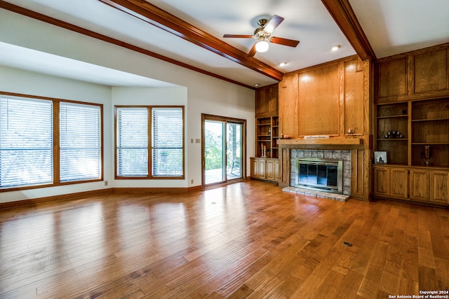 unfurnished living room with ceiling fan, hardwood / wood-style flooring, beamed ceiling, and ornamental molding