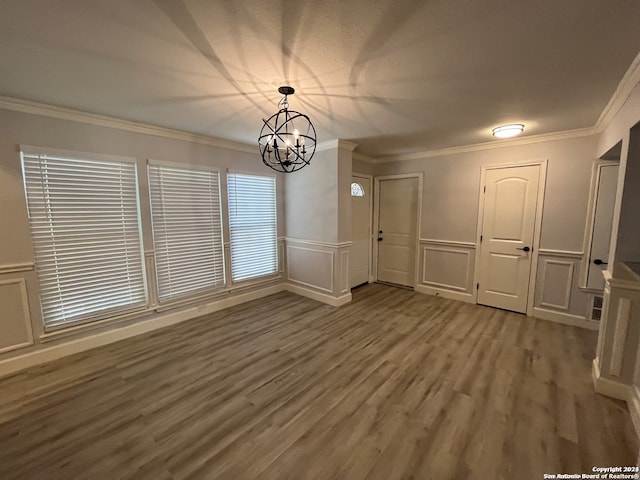 unfurnished dining area with hardwood / wood-style flooring, ornamental molding, and a chandelier