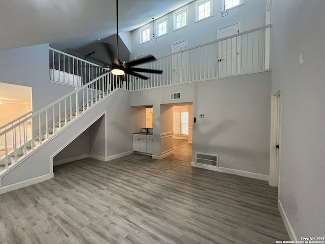 unfurnished living room with wood-type flooring, high vaulted ceiling, and ceiling fan