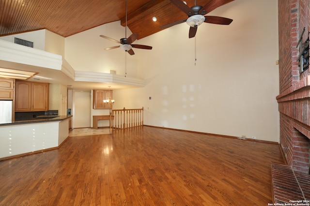 unfurnished living room with ceiling fan with notable chandelier, a fireplace, hardwood / wood-style floors, wooden ceiling, and high vaulted ceiling