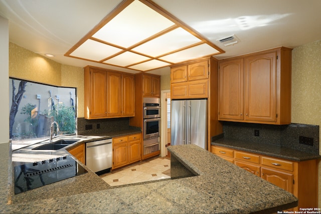 kitchen featuring appliances with stainless steel finishes, sink, and dark stone counters