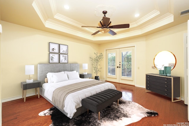 bedroom with french doors, access to exterior, a tray ceiling, dark hardwood / wood-style flooring, and ceiling fan