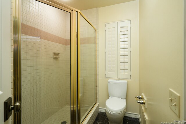 bathroom featuring toilet and a shower with shower door