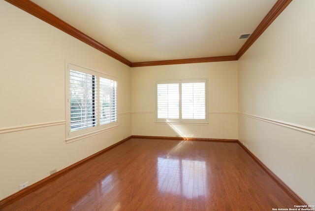 empty room featuring ornamental molding and hardwood / wood-style flooring