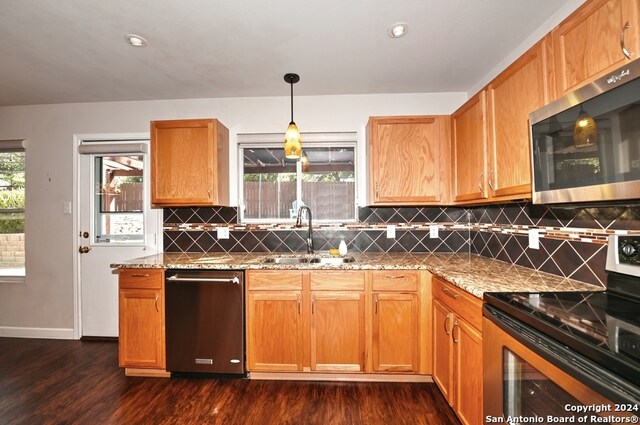 kitchen with appliances with stainless steel finishes, decorative light fixtures, sink, and dark wood-type flooring