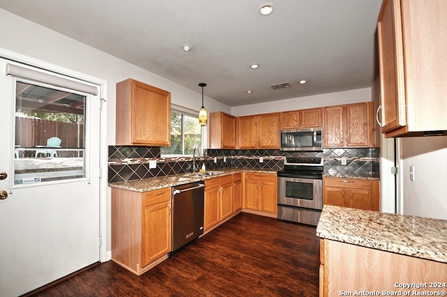 kitchen featuring sink, stainless steel appliances, decorative light fixtures, light stone counters, and dark hardwood / wood-style floors