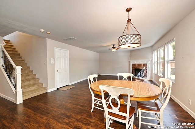 dining space with ceiling fan, dark hardwood / wood-style flooring, and a fireplace