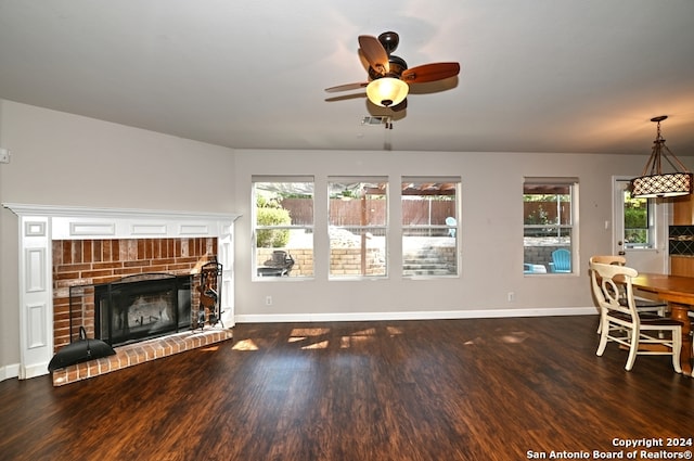 living room with ceiling fan, a healthy amount of sunlight, dark hardwood / wood-style flooring, and a brick fireplace