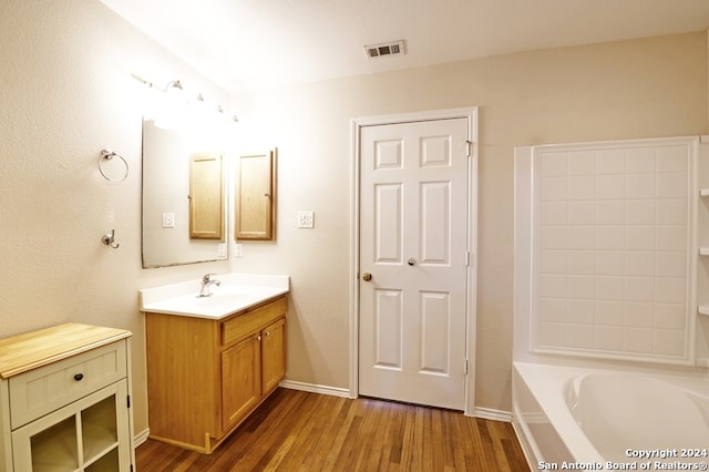 bathroom featuring vanity, a tub to relax in, and wood-type flooring