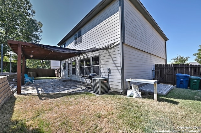 rear view of house featuring a patio area, central AC, and a lawn