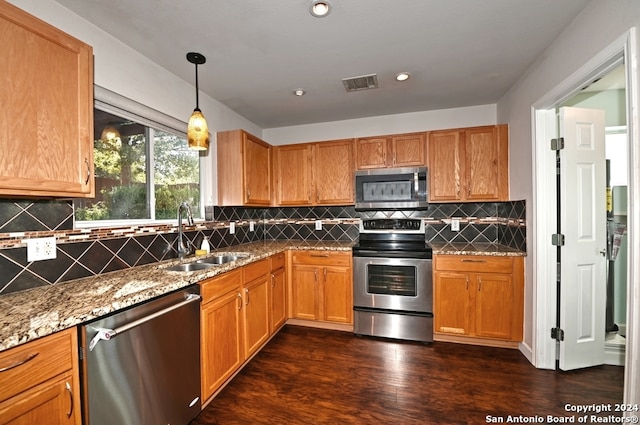 kitchen featuring hanging light fixtures, dark hardwood / wood-style floors, stainless steel appliances, sink, and light stone counters