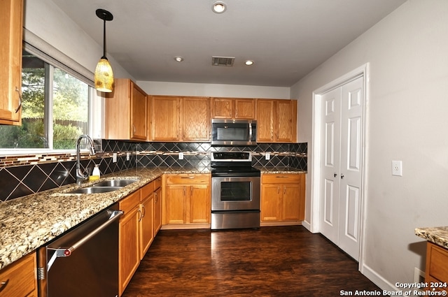 kitchen with dark wood-type flooring, hanging light fixtures, backsplash, sink, and appliances with stainless steel finishes