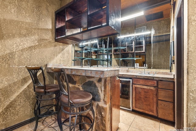 bar featuring wine cooler, sink, and light tile patterned floors