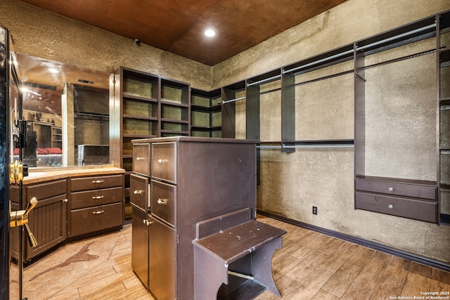 walk in closet featuring built in desk and light wood-type flooring