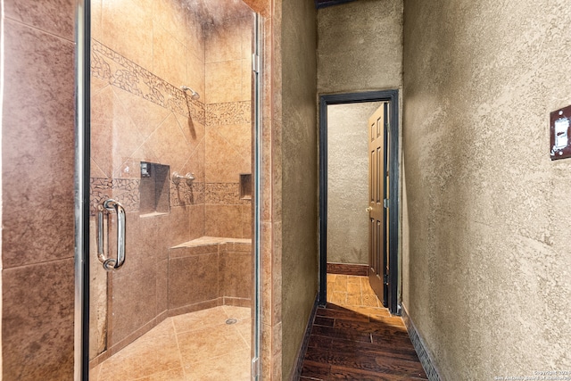 bathroom with an enclosed shower and wood-type flooring