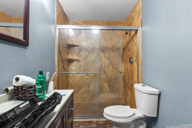 bathroom featuring vanity, a shower with shower door, and toilet