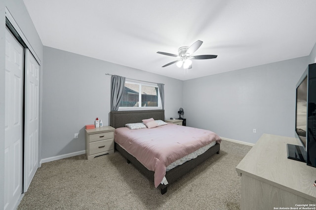 bedroom with a closet, ceiling fan, and light colored carpet