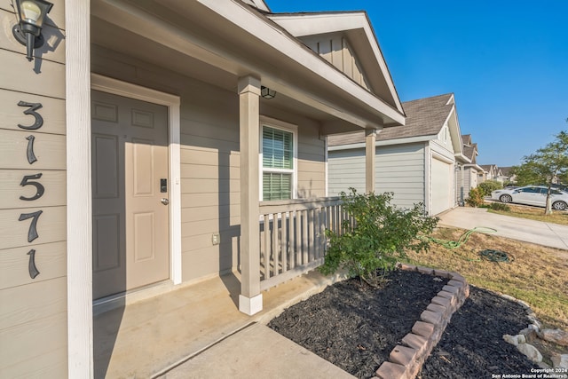 view of exterior entry featuring a porch and a garage