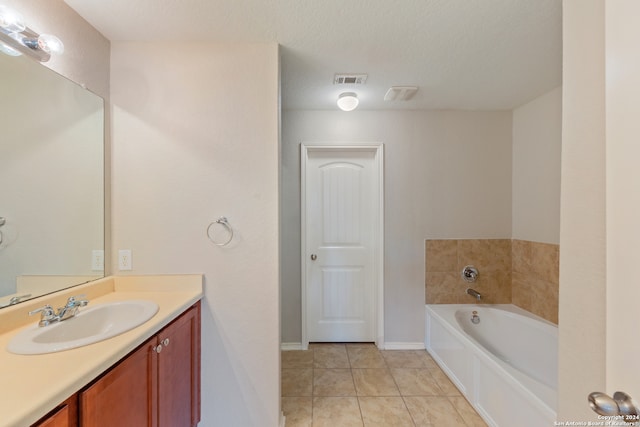 bathroom featuring vanity, a textured ceiling, a bath, and tile patterned floors