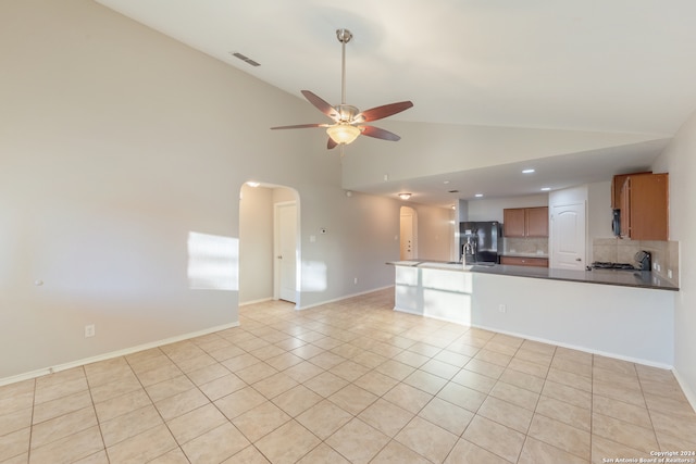 kitchen featuring black refrigerator with ice dispenser, tasteful backsplash, light tile patterned floors, high vaulted ceiling, and ceiling fan