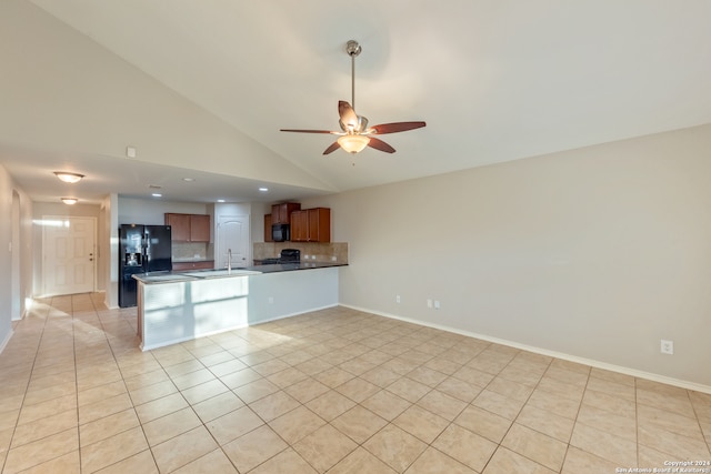 kitchen featuring kitchen peninsula, light tile patterned floors, backsplash, and black fridge