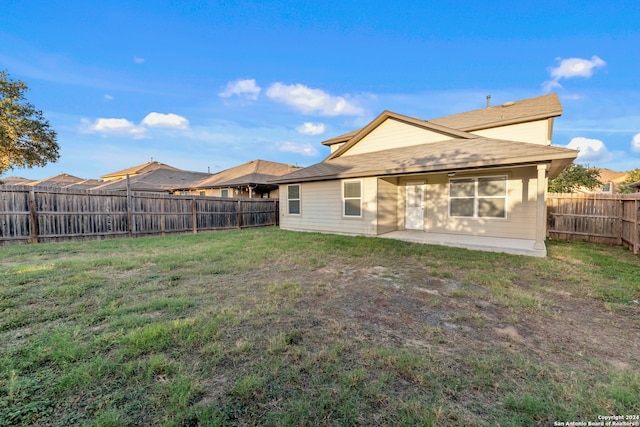 back of house with a patio area and a lawn