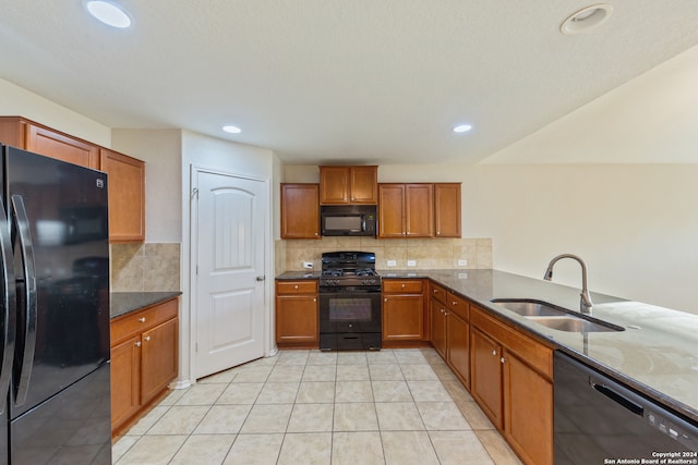 kitchen featuring sink, black appliances, decorative backsplash, and dark stone counters