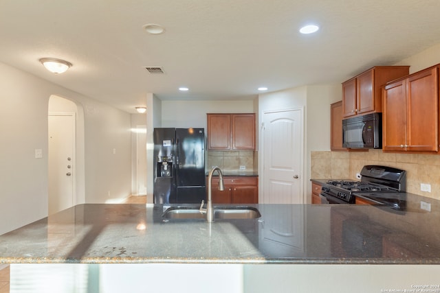 kitchen with kitchen peninsula, black appliances, sink, and dark stone counters