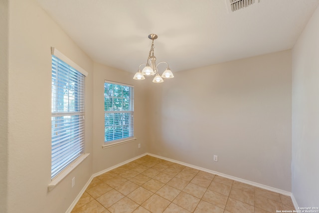 tiled spare room with an inviting chandelier