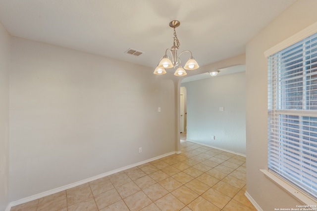 unfurnished room with a chandelier and light tile patterned floors