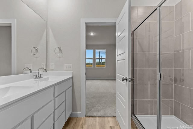 bathroom with a shower with shower door, vanity, and hardwood / wood-style flooring