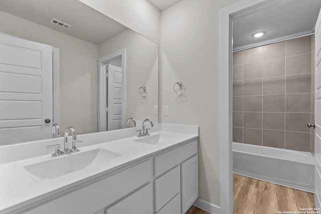 bathroom featuring wood-type flooring, tiled shower / bath combo, and vanity