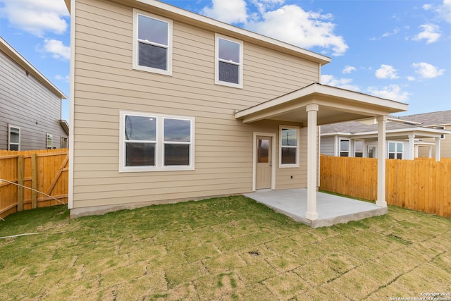 rear view of property featuring a lawn and a patio area