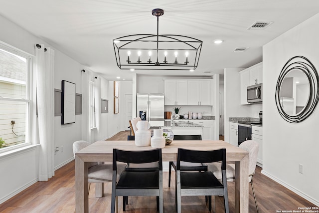 dining space with light hardwood / wood-style floors and an inviting chandelier