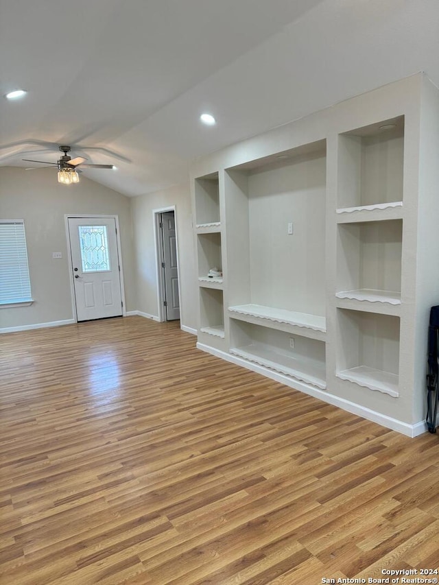 unfurnished living room featuring lofted ceiling, light hardwood / wood-style flooring, built in shelves, and ceiling fan