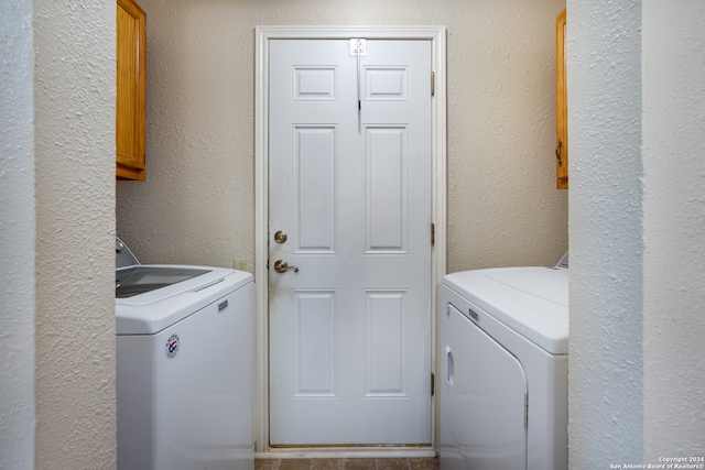 clothes washing area featuring separate washer and dryer and cabinets