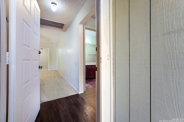 corridor with wood-type flooring and a textured ceiling