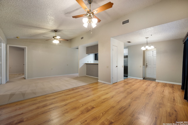 unfurnished living room featuring a textured ceiling, light wood-type flooring, and ceiling fan with notable chandelier