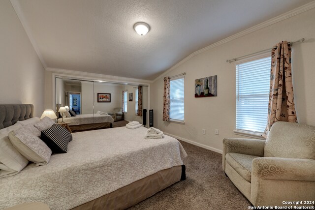 bedroom with crown molding, vaulted ceiling, carpet flooring, and a textured ceiling