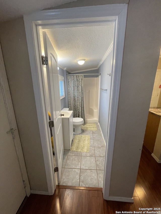 bathroom featuring crown molding, wood-type flooring, a textured ceiling, toilet, and walk in shower