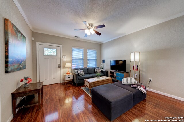 living room with dark wood-type flooring, ceiling fan, crown molding, and a textured ceiling