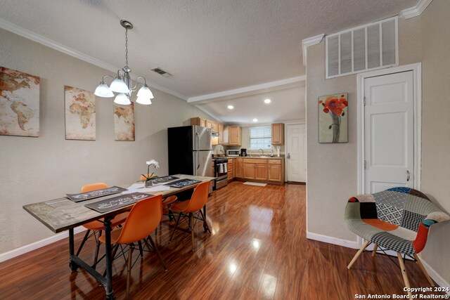 dining space featuring hardwood / wood-style flooring, ornamental molding, a chandelier, and sink