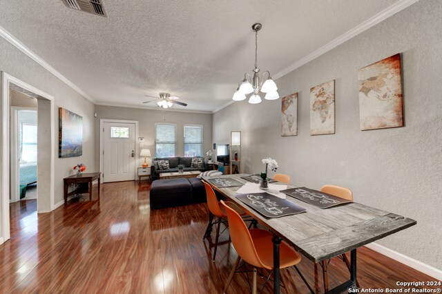 dining space with ceiling fan with notable chandelier, ornamental molding, dark hardwood / wood-style floors, and a textured ceiling