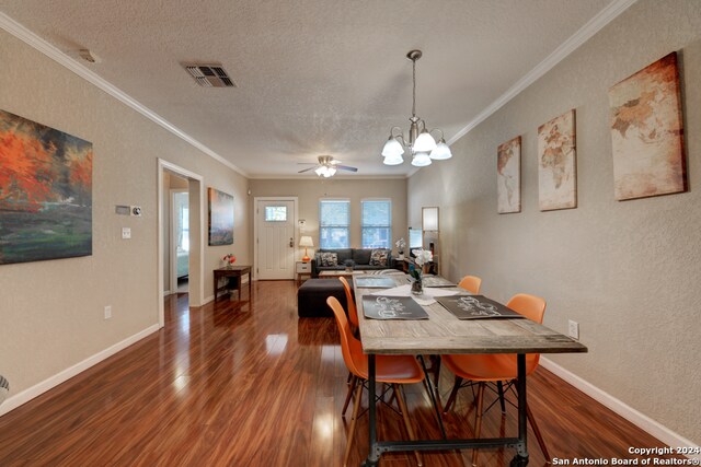 dining area featuring dark wood-type flooring, crown molding, and a textured ceiling