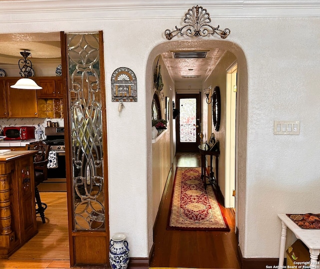 corridor featuring crown molding, a textured ceiling, and hardwood / wood-style flooring