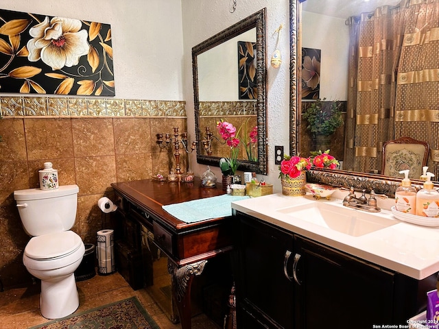 bathroom with toilet, vanity, and tile walls