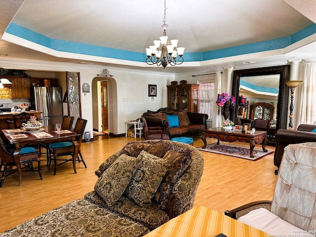 living room featuring ornamental molding, hardwood / wood-style floors, and a raised ceiling